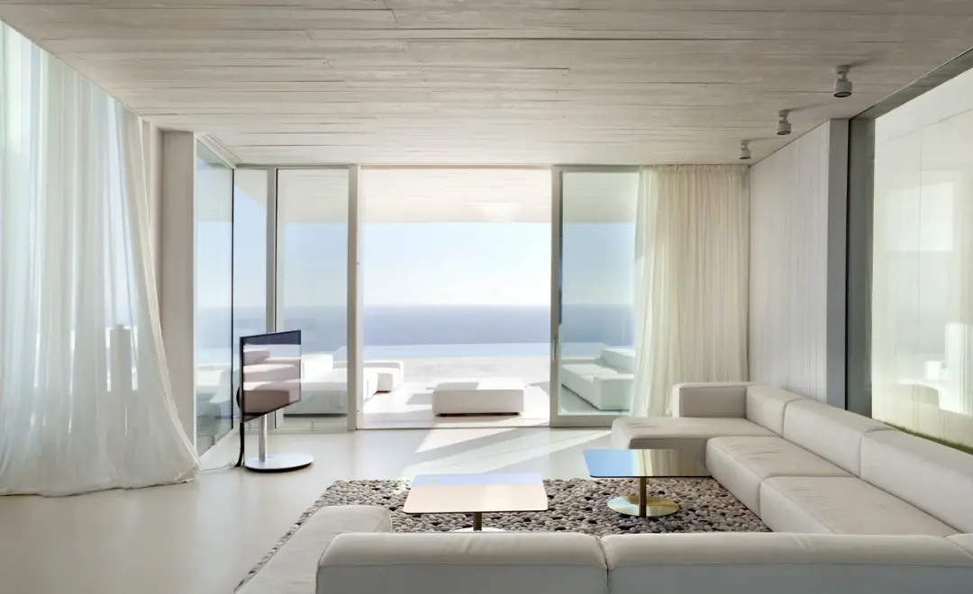 Salón minimalista con suelo de microcemento blanco y vistas panorámicas al mar en Elche