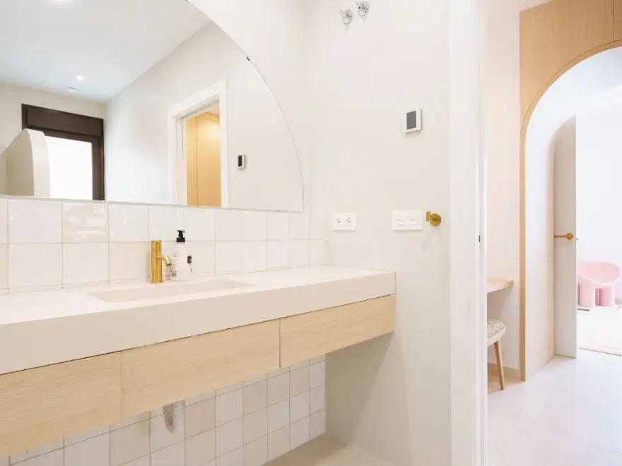 Baño minimalista con microcemento blanco, encimera de madera y lavabo alargado en Elche