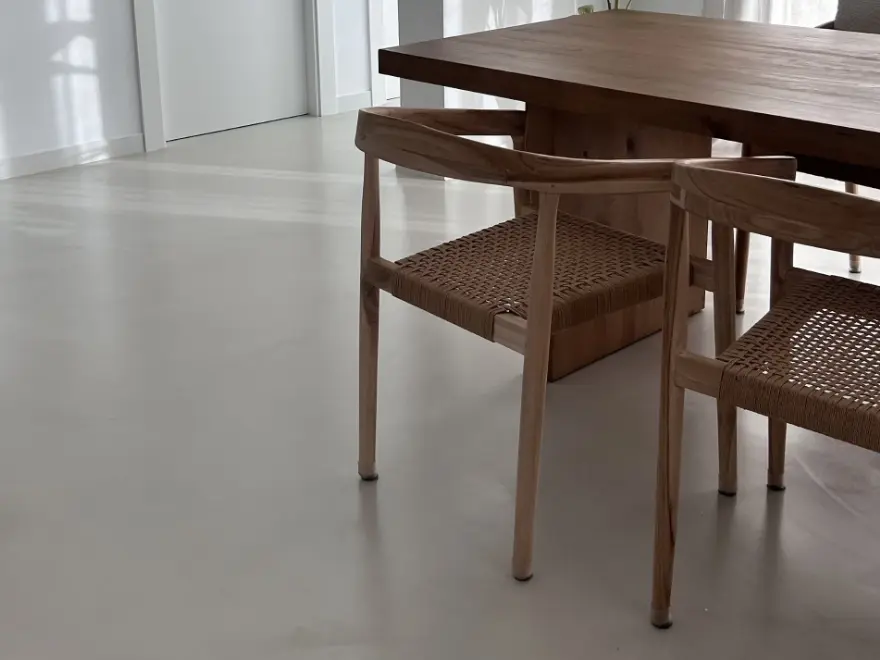 Detalle de suelo de microcemento gris con mueble auxiliar de madera en vivienda de Elche