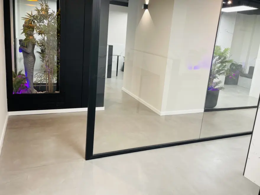 Espacio diáfano con suelo de microcemento blanco y columna metálica negra en local de Elche