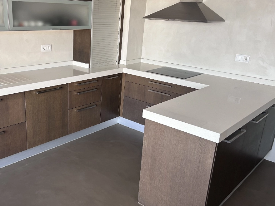Cocina con microcemento gris, isla central y campana extractora en Elche