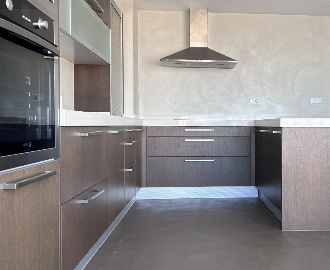 Cocina con microcemento gris, isla central y campana extractora en Elche