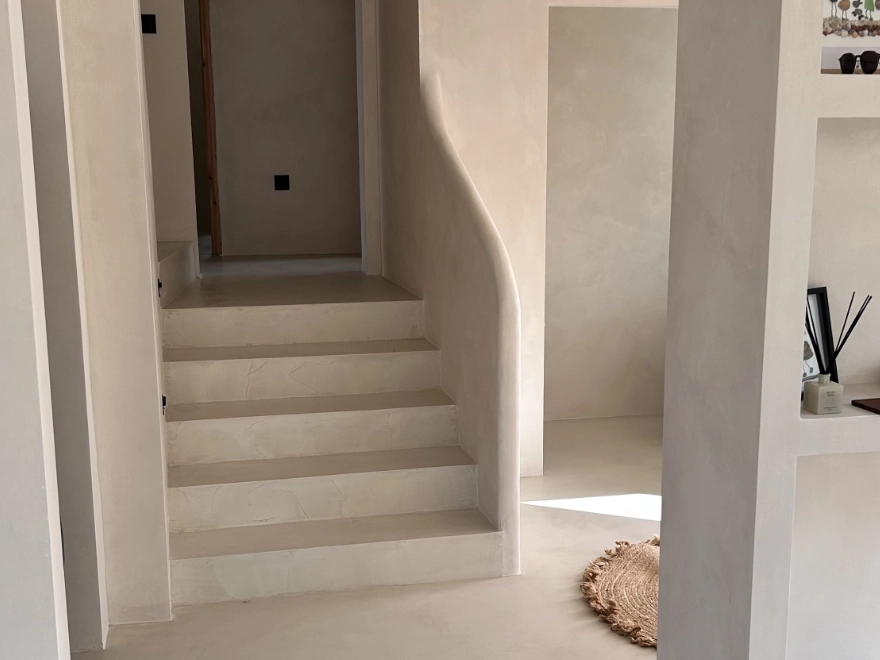 Escalera con microcemento beige y barandilla metálica negra en Elche