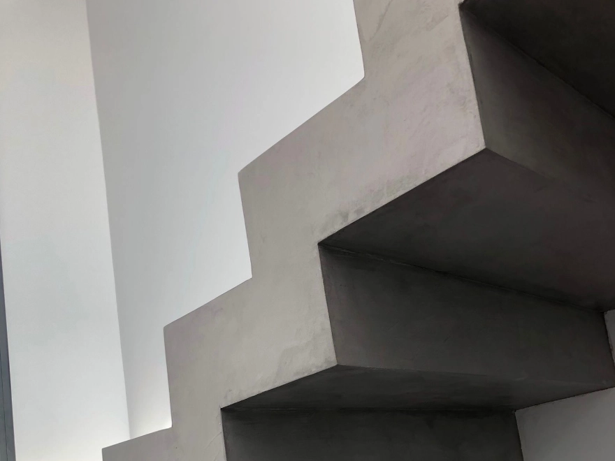 Escalera con microcemento blanco y barandilla de madera en vivienda de Elche