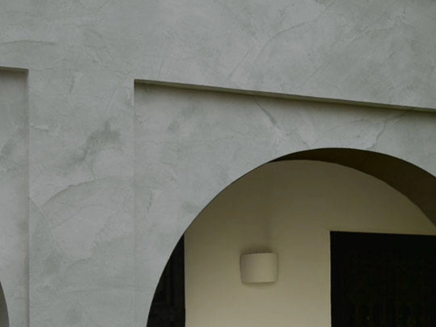 Detalle de pared con microcemento gris claro y arco en fachada exterior en Elche