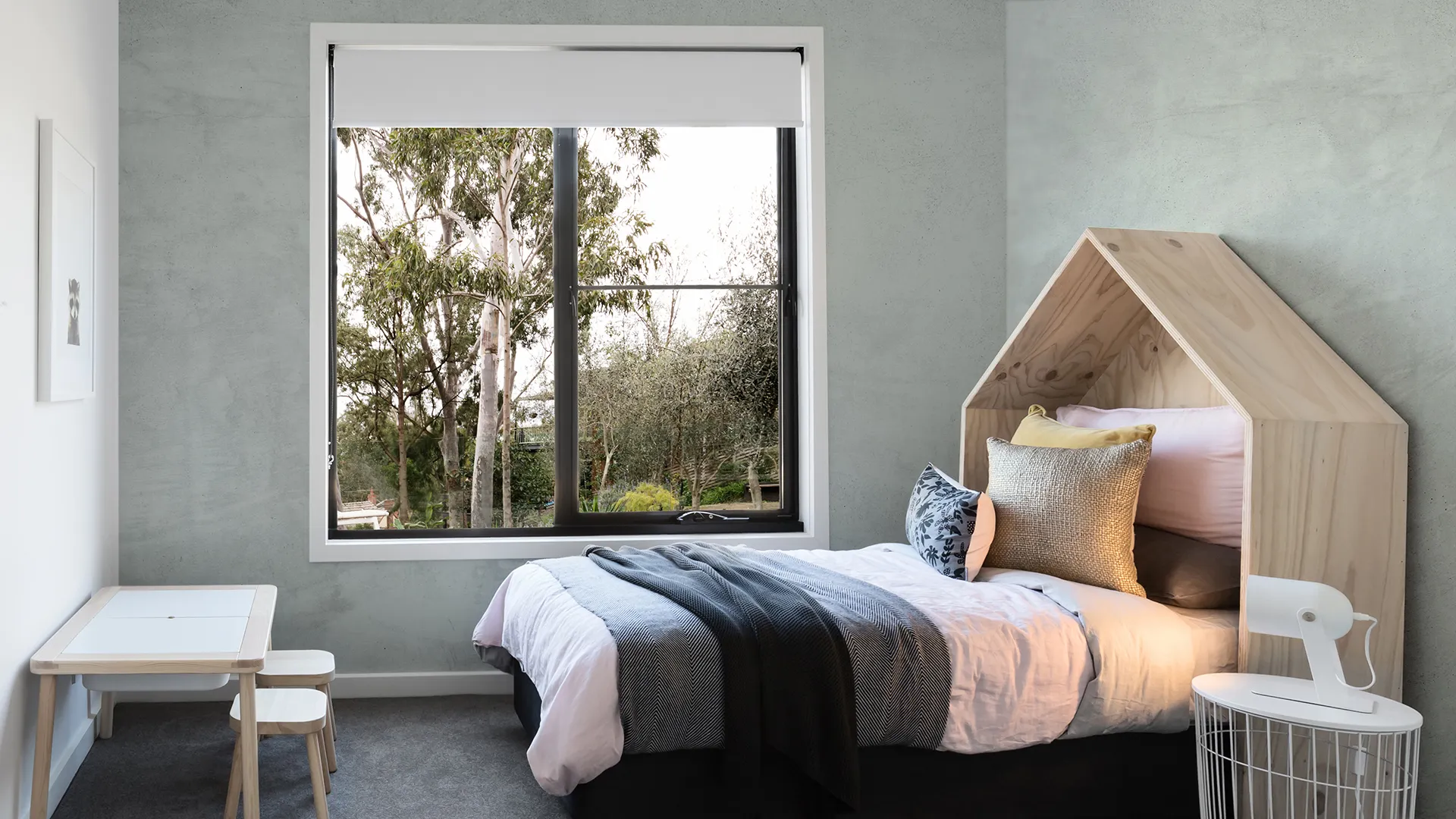 Habitación infantil con pared de microcemento verde grisáceo y cama con cabecero de madera en Elche