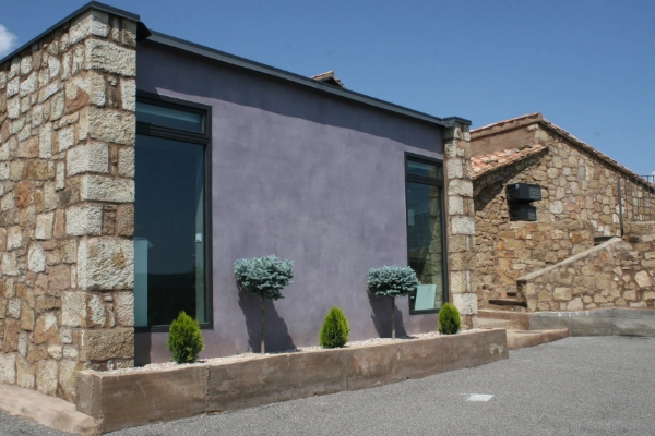 Fachada exterior con microcemento gris violáceo y esquinas de piedra natural en vivienda de Elche