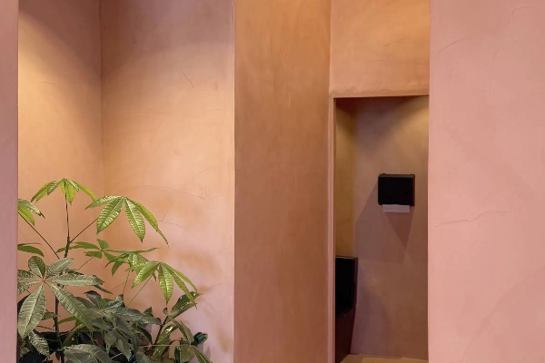 Detalle de paredes y techo con microcemento en tono rosa salmón y nichos con iluminación empotrada en Elche