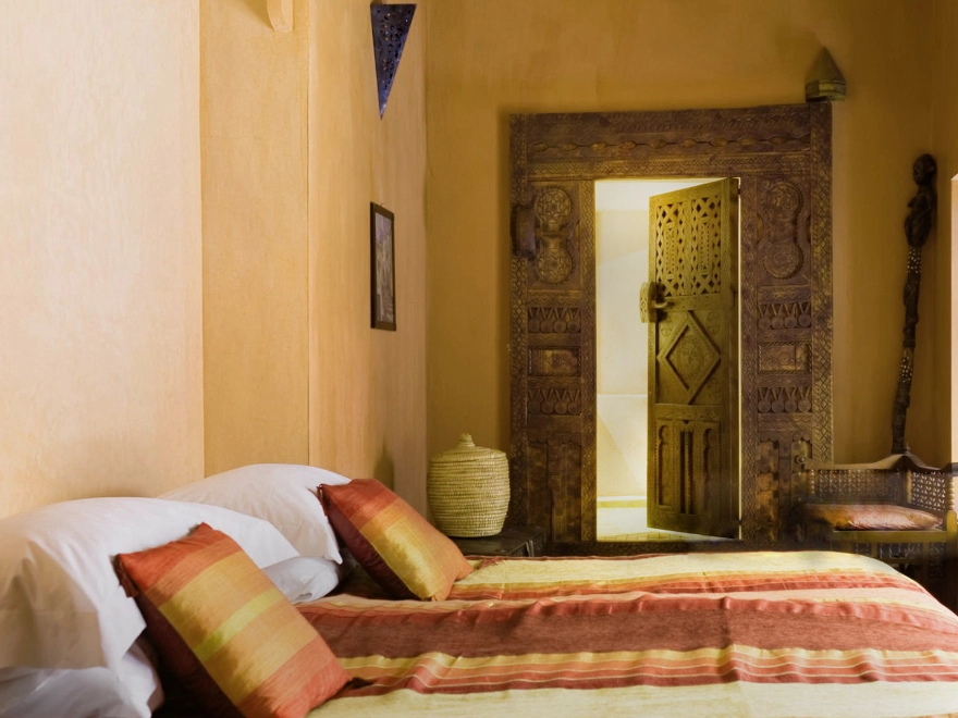 Dormitorio con microcemento en tono tierra y puerta dorada en Elche