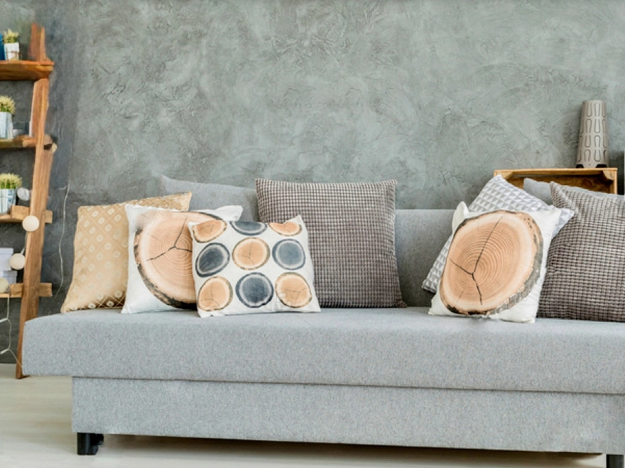 Salón con microcemento beige, sofá gris y decoración natural en Elche