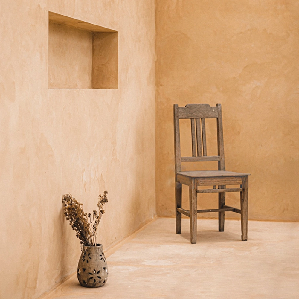 Pared y suelo de microcemento en tono tierra ocre con nicho y decoración rústica en Elche