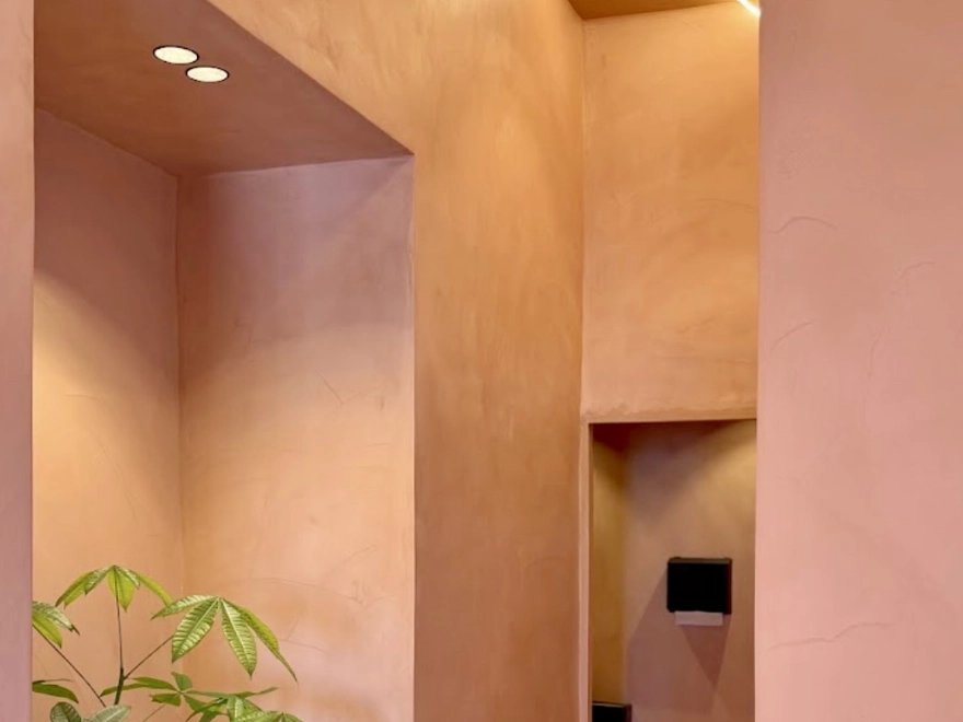 Detalle de paredes y techo con microcemento en tono rosa salmón y nichos con iluminación empotrada en Elche