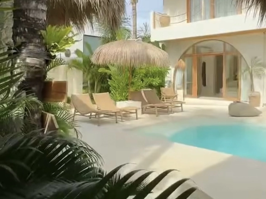 Zona de piscina exterior con suelo de microcemento blanco y fachada con arco mediterráneo en Elche