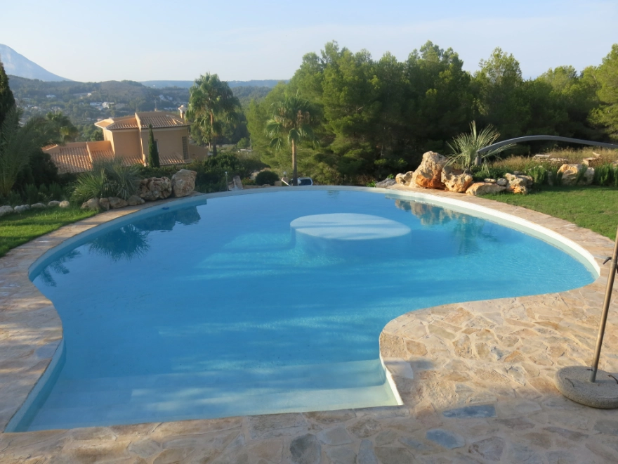 Piscina de forma orgánica con microcemento azul turquesa y vistas al paisaje mediterráneo en Elche