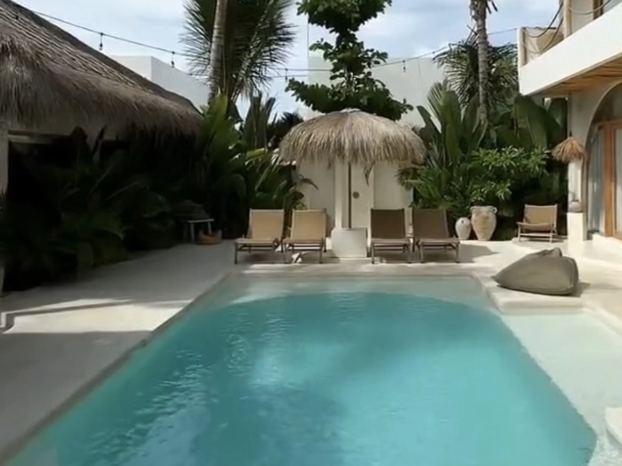 Borde de piscina con microcemento beige y muro de piedra natural en exterior de Elche