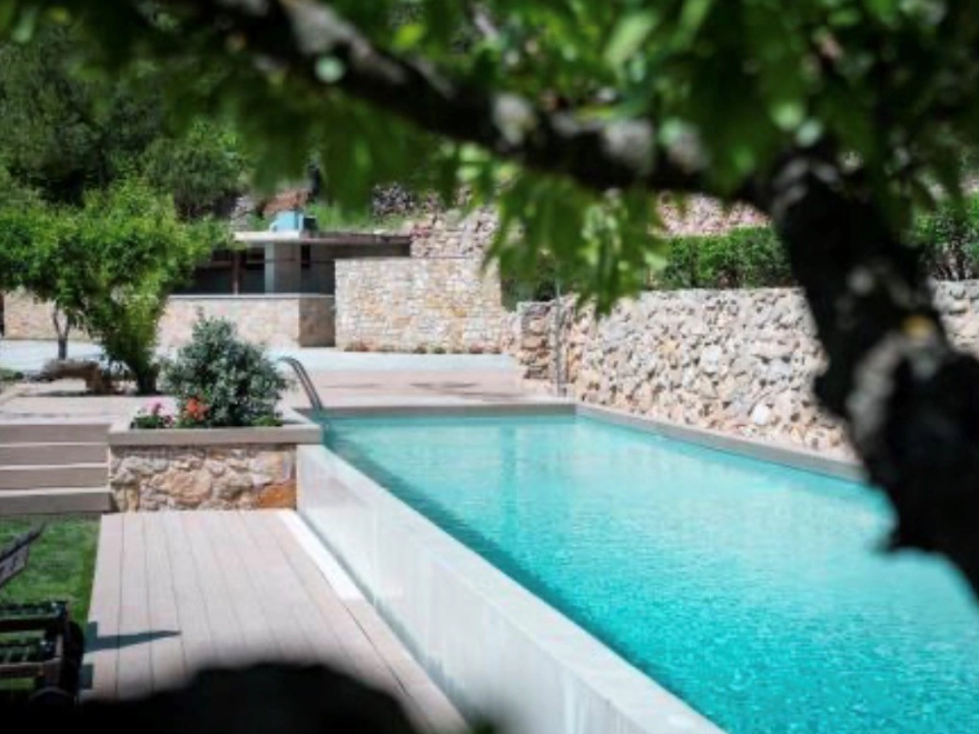 Piscina exterior con microcemento azul turquesa y palapa tropical en chalet de Elche