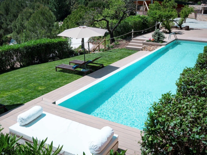 Piscina rectangular con microcemento turquesa y terraza de madera en jardín de chalet en Elche