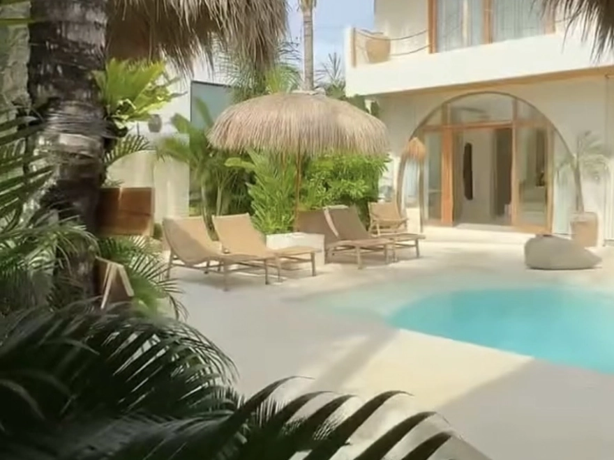 Zona de piscina exterior con suelo de microcemento blanco y fachada con arco mediterráneo en Elche